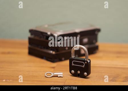 Computer hard disks and metal padlock symbolizing concept for encrypted data, cyber security on wooden desk Stock Photo