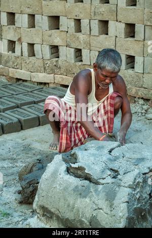 In West Bengal, India, a casual laborer diligently prepares soil for traditional clay brick production, embodying the region's rich heritage and craft Stock Photo