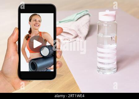 Online video workout, female fitness coach on screen of smart phone in hand. Composite photo. Stock Photo