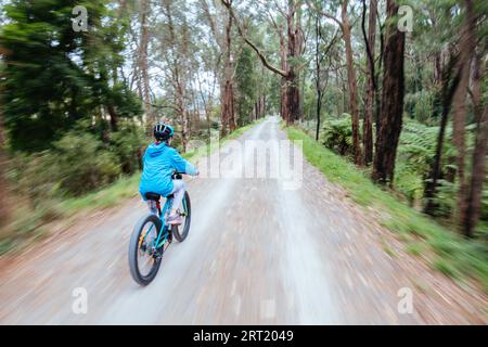 A child cycles at speed in Mt Evelyn on the popular Lilydale to Warburton Rail Trail on a warm autumn day in Victoria, Australia Stock Photo