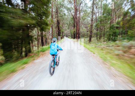 A child cycles at speed in Mt Evelyn on the popular Lilydale to Warburton Rail Trail on a warm autumn day in Victoria, Australia Stock Photo