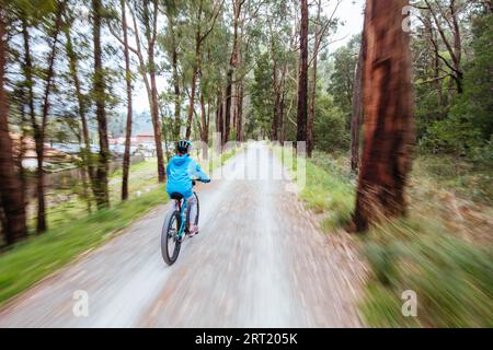 A child cycles at speed in Mt Evelyn on the popular Lilydale to Warburton Rail Trail on a warm autumn day in Victoria, Australia Stock Photo