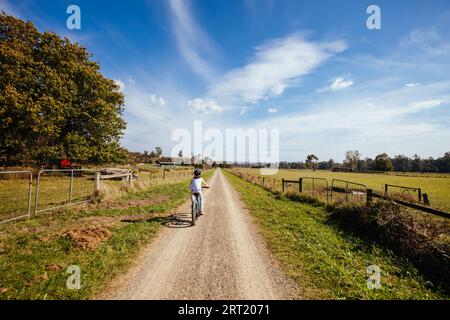 A child cycles at speed in Mt Evelyn on the popular Lilydale to Warburton Rail Trail on a warm autumn day in Victoria, Australia Stock Photo