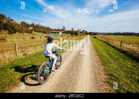 A child cycles at speed in Mt Evelyn on the popular Lilydale to Warburton Rail Trail on a warm autumn day in Victoria, Australia Stock Photo