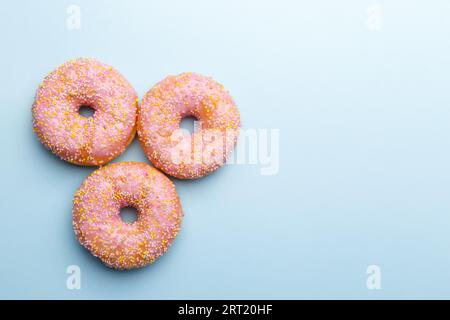 Pink doughnuts and candies on blue background, copy space flat lay Stock Photo