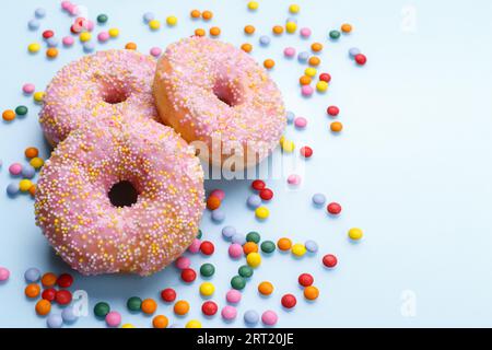 Pink doughnuts and candies on blue background, copy space flat lay Stock Photo