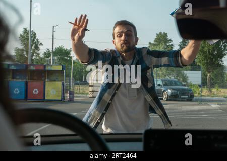 Male instructor showing stop with hands while teaching to park a car. Driving test, driver courses, exam concept Stock Photo
