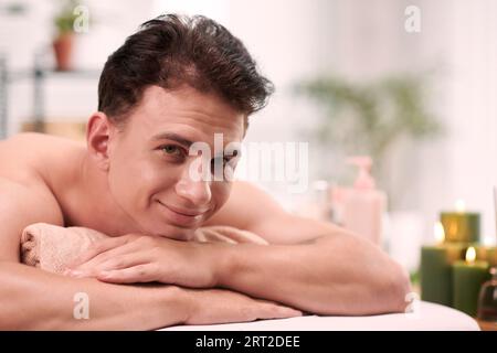 Portrait of cheerful young man resting on bed after relaxing massage Stock Photo