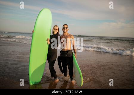 Portrait of beautiful young couple with surfboards posing on the beach together Stock Photo