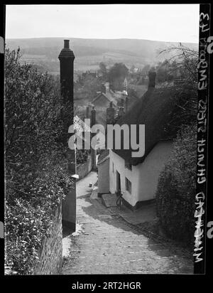 Minehead, West Somerset, Somerset, 1940-1948. View of Church Steps from the top, overlooking parts of Minehead, and looking down the hill towards Vicarage Road at the bottom. Cob walled cottages line the steps and a prominent exterior stack is on the left side of the image. In the distance, past the various rooftops is a landscape of agricultural land. Stock Photo