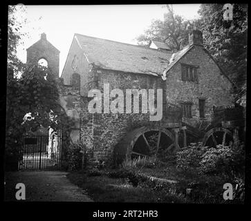 Castle Mill, Mill Lane, Dunster Park, Dunster, West Somerset, Somerset, 1940-1949. A view of Dunster Castle Mill, an 18th century water mill attached to a gateway. View of Dunster castle mill which was rebuilt between 1779-1782 and a gateway to the left. The mill is a two storey building with additional attics and the gateway is attached to the left side of the wall which the water mill protrudes from. The gateway is a rubble wall with a pointed arch opening, with iron gates underneath. The site is now looked after by the National Trust Stock Photo