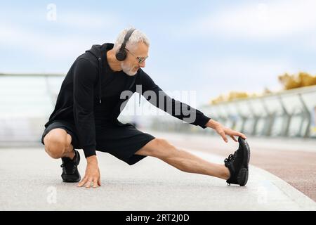 Determined elderly man stretching body, have outdoor workout Stock Photo