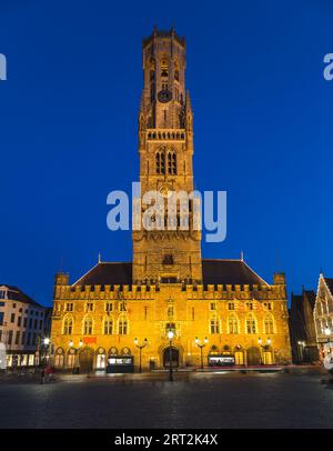 View of the Belfry of Bruges at dusk from Grote Markt (Great Market Square) with a blue sky in the background. Stock Photo