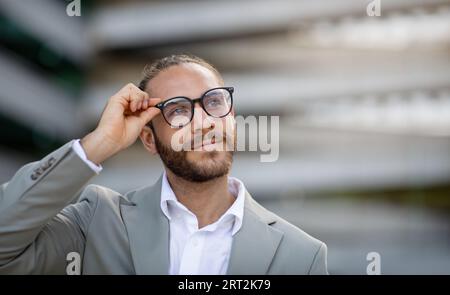 Handsome Young Businessman In Stylish Eyeglasses Standing Outdoors On City Street Stock Photo