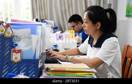 (230910) -- HAIKOU, Sept. 10, 2023 (Xinhua) -- Fu Yaohui (front) prepares for a class at Hainan (Haikou) Special School in Haikou, south China's Hainan Province, Sept. 6, 2023. Fu Yaohui is a teacher at the special education school in Haikou. Since 2004, Fu has been engaged in special education for students with intellectual disabilities, cultivating their basic skills to adapt to life. Every day, Fu arrives at school early and accompanies the students with patience and encouragement. 'I want my students to be self-reliant,' she said. In order to achieve this goal, she tries her best to help Stock Photo