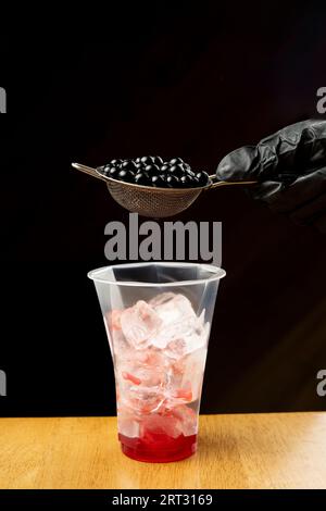 Jelly bubble tea balls and plastic cup with ice on dark black background Stock Photo