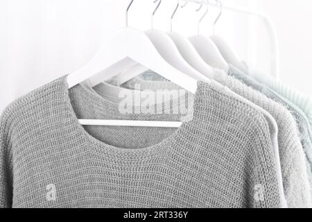 Warm knitted, autumn, winter clothes hanging on a rack, trending concept, pastel colors Stock Photo