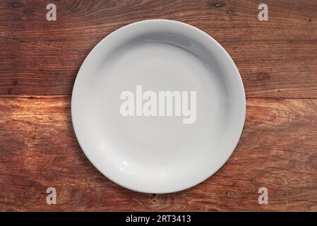 Empty ceramic round white plate on wood background Stock Photo