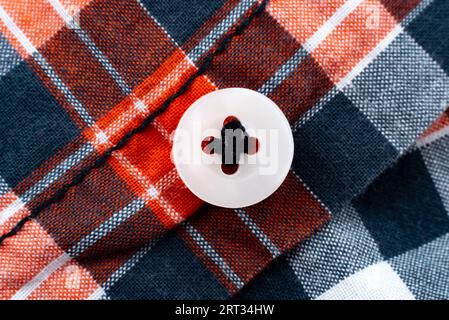 Close-up of a button on a plaid shirt. Button Stock Photo
