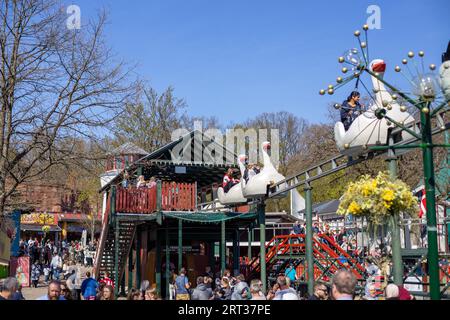 Copenhagen, Denmark, April 21, 2019: Amusement park ride and crowd of people at Bakken, the oldest amusement park in the world Stock Photo