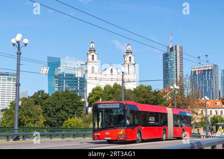 VILNIUS, LITHUANIA - 3RD SEPT 2023: A common red public transportation bus in Vilnius during the day with architecture in the background. People can b Stock Photo