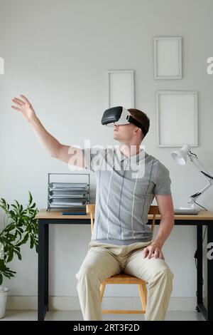 Developer in headset testing new virtual reality application at home Stock Photo