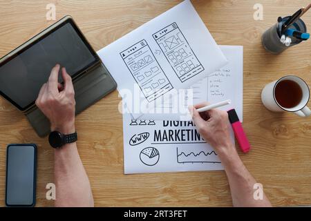 UI designer working on mobile app wireframe and analyzing marketing strategy Stock Photo