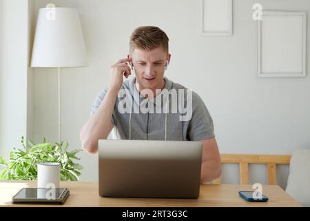 Portrait of young businessman wearing earbuds when video calling coworker Stock Photo
