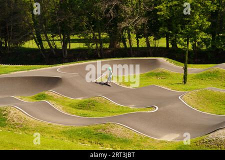Langeac, France - May 27, 2023: A boy in a protective helmet and knee pads learn to ride a skateboard on a special track. Sport activity concept Stock Photo