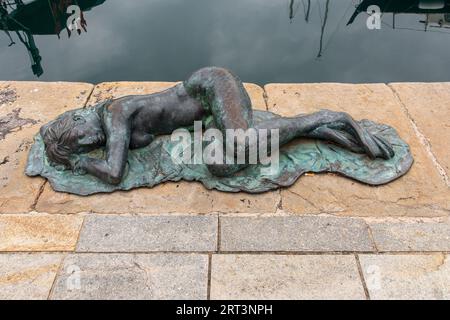 Bronze sculpture 'Sleeping mermaid' ('Sirenetta Dormiente') by Giampaolo Parini on the quay of the Old Dock ('Vecchia Darsena') Savona, Liguria, Italy Stock Photo