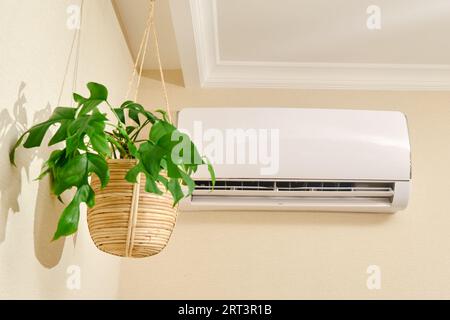 The white air conditioner controls the temperature in the living room of the house. Stock Photo