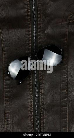 Black sunglasses on leather jacket Stock Photo