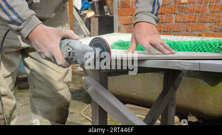 grinding the edge of a stone tile with a miter saw, an emery attachment on a grinder in the process of processing stone tiles Stock Photo