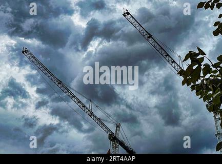 Construction cranes against a stormy sky Stock Photo