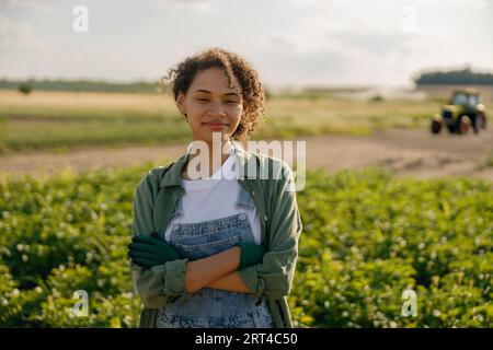 Smiling female agronomist standing with crossed hands on the field background. High quality photo Stock Photo