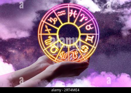 Astrology. Woman holding zodiac wheel against starry night sky with clouds, closeup Stock Photo