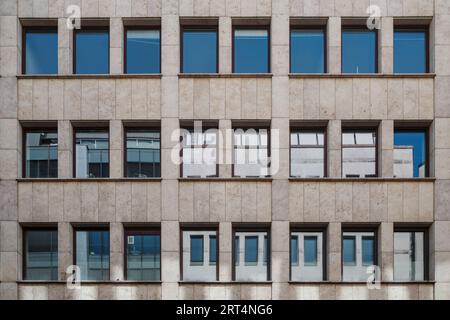 Outdoor front exterior view of typical old modern with rectangular windows on grid arrangement system on cream granite stone facade wall. Stock Photo
