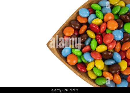 pile of colorful chocolate candies in wooden bowl on white background, top view Stock Photo