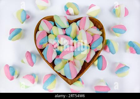 pile of marshmallow candies on a heart shaped wooden bowl on white background Stock Photo
