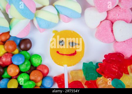 piles of various kinds of sweets and candies with a focus on the smiling candy Stock Photo