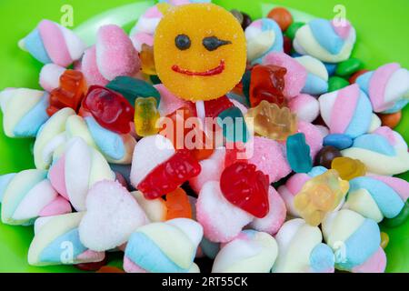 piles of various kinds of sweets and candies with a focus on the smiling candy Stock Photo