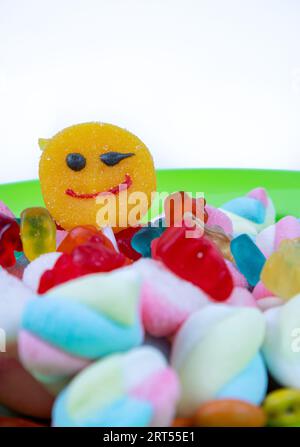 piles of various kinds of sweets and candies with a focus on the smiling candy Stock Photo