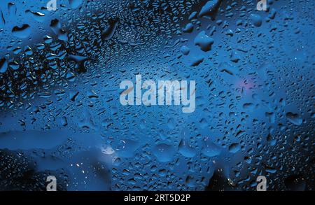 Raindrops on a clear window create a wet and rainy background. Stock Photo