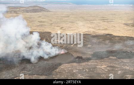 closeup aerial view of erupting Litli-Hrutur volcano near Reykjavik Iceland showing flames from the hot lava surrounded by smoke and haze Stock Photo