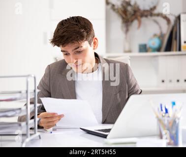Male bookkeeper doing paperwork in workplace in office - checks accounting documents Stock Photo