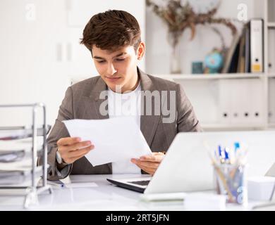 Male bookkeeper doing paperwork in workplace in office - checks accounting documents Stock Photo