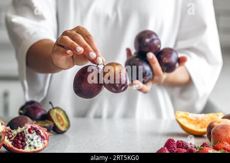 Plums in the hands of a woman in the kitchen. Stock Photo