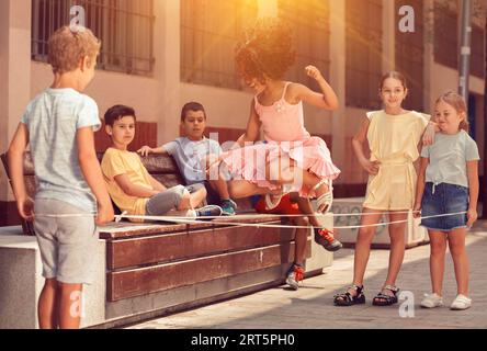 Mexican girl playing rubber band jumping game with european friends Stock Photo