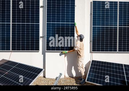 Man installing solar panels on a rooftop Stock Photo