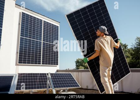 Man installing solar panels on a rooftop Stock Photo
